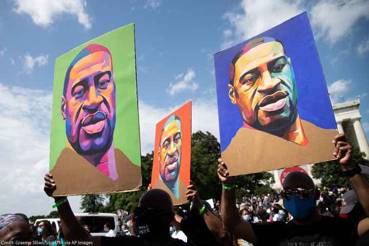 Protesters holding signs depicting George Floyd.