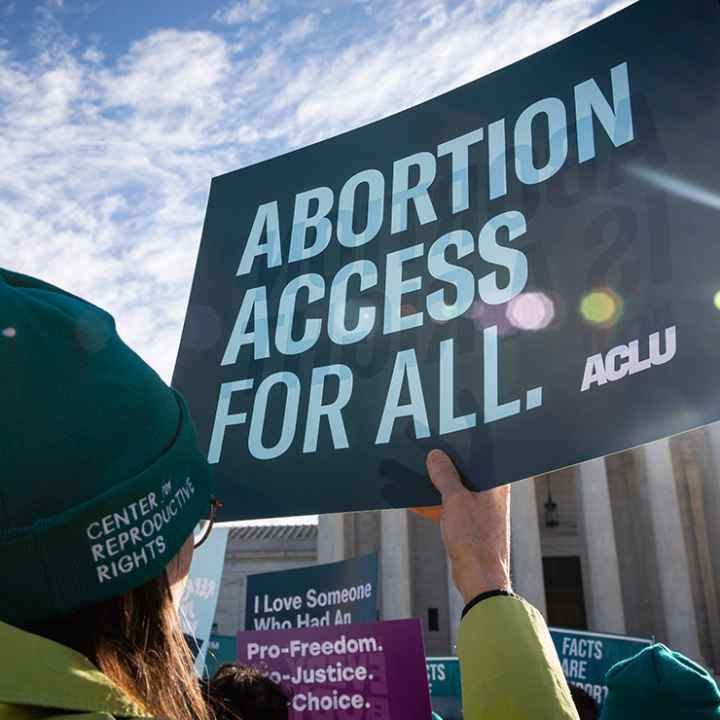 Person holds up ACLU sign that reads "Abortion Access for All" in front of the Supreme Court building.