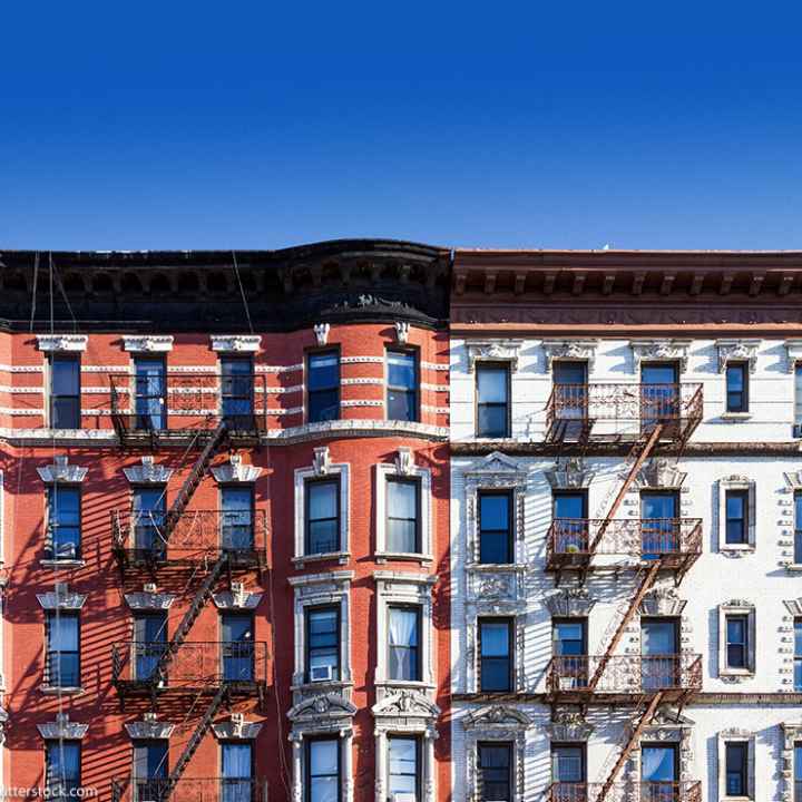 New York City block of old historic apartment buildings in the East Village of Manhattan, with clear blue sky background.