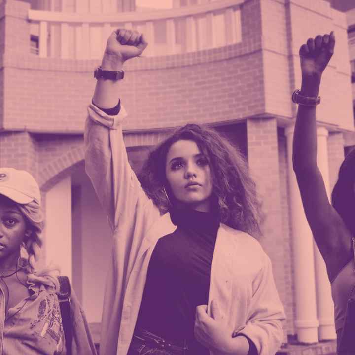 Girls in protest raising fists on pink background