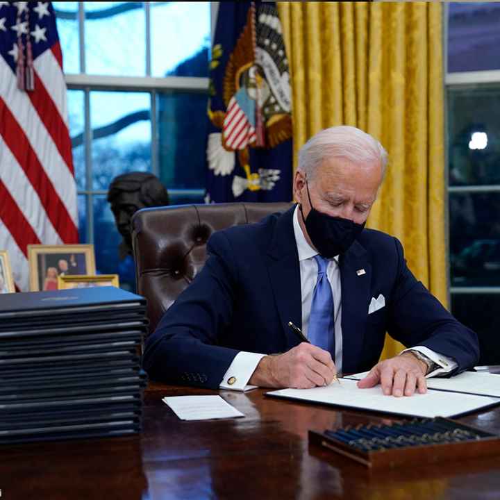 President Joe Biden signs his first executive order in the Oval Office of the White House.